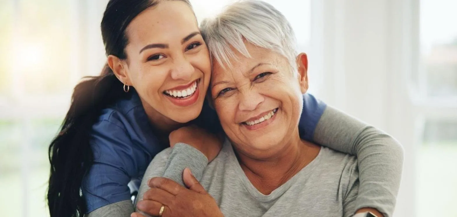 Smiling Always Responsive caregiver hugging a senior client at home