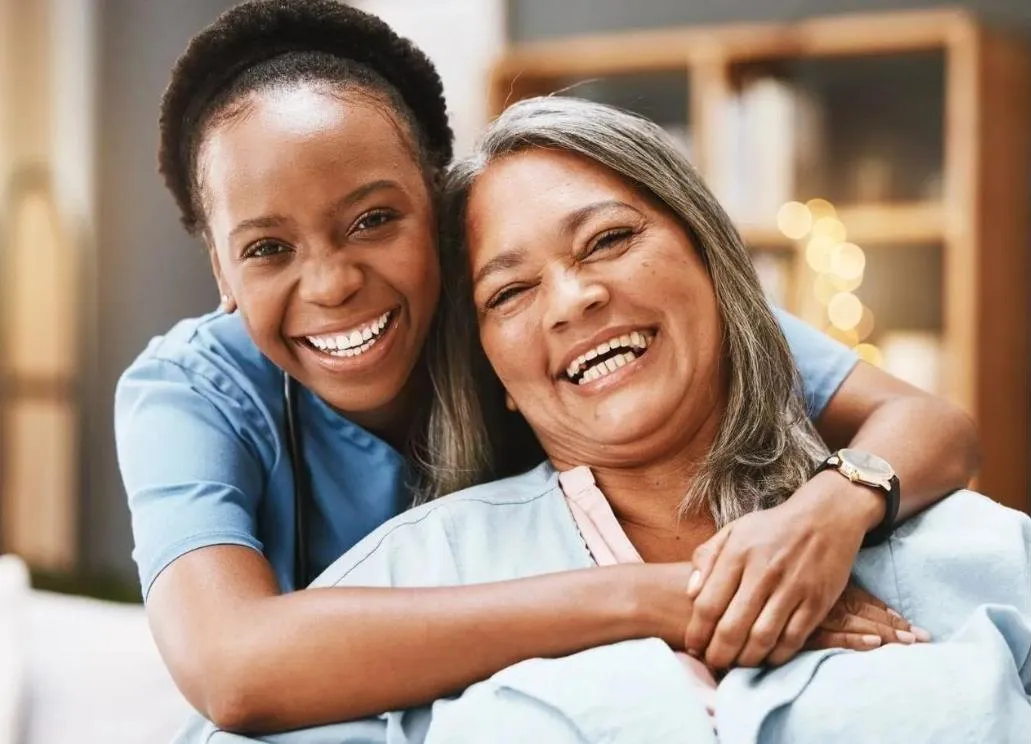 Caregiver and senior woman smiling together at home